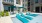 a pool with a lounge chair and umbrellas by a building